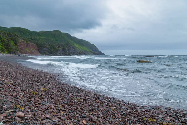 A rocky beach next to rough ocean water - Gros Morne, Newfoundland, Canada.