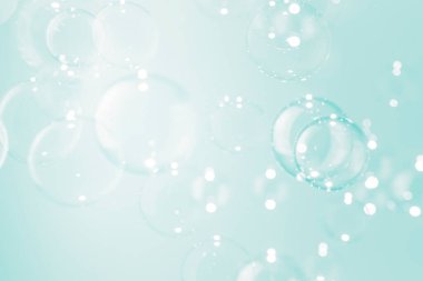 Güzel bulanık, şeffaf sabun köpükleri yumuşak yeşil arka planda yüzerler..