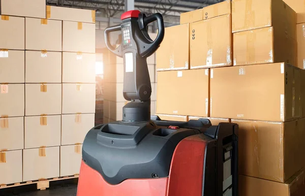 Electric forklift pallet jack with cargo shipment boxes. Stack of cardboard boxes on pallet rack at the warehouse storage. Manufacturing and warehousing.