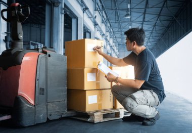Asyalı İşçi Holding Panosu Depo 'da Envanter Yönetimi yapıyor. Stok Paket Kutuları Denetleniyor.