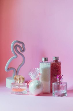 Banyo aksesuarları küçük bir vazonun yanında çiçek ve pembe arka planda flamingo lambası..