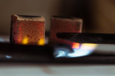 Hindistan cevizi nargilesi kömürleri gaz sobasının üzerinde durur ve evde ya da nargile barında ısınır..