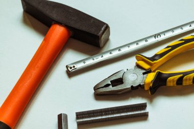 Bir çekiç, kerpeten ve beyaz arka planda mezura yanında metal uğursuz anahtarlar..