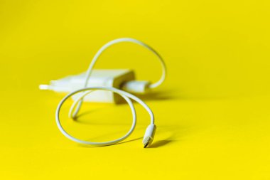 Parlak sarı arka planda mikro kabzalı beyaz şarj aleti..