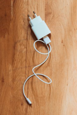 Kablolu beyaz şarj aleti ahşap arka planda.