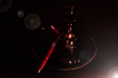 Siyah arka planda küçük siyah nargile ve fotoğrafın köşesinde bir lens ışığı var..