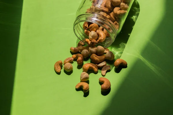 Scattered Nuts Glass Jar Green Background Hazelnuts Cashews — Stock Photo, Image