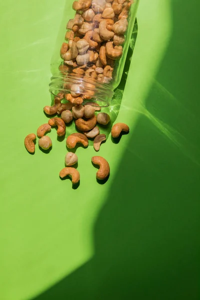 Scattered Nuts Glass Jar Green Background — Stock Photo, Image