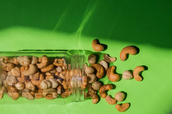 Scattered Nuts Glass Jar Green Background Hazelnuts Cashews — Fotografia de Stock