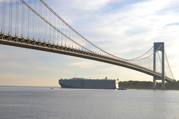巨大的贸易船经过纽约城最大的桥下 免版税图库照片