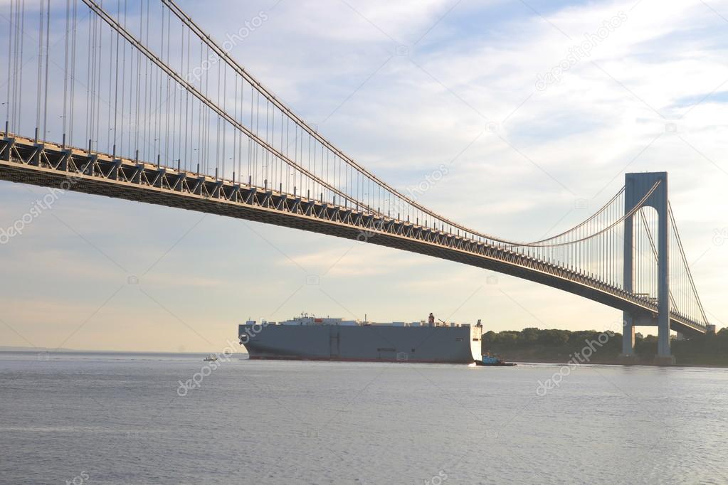 Large trade ship passes under the largest bridge in New York City