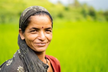 ALMORA, INDIA - 6 Kasım 2020: Hintli bir kadın çiftçinin portresi yeşil tarlalarda çalışıyor, gülümsüyor ve kameraya bakıyor.