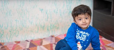 Genç Hintli çocuk mavi kazak giyip oyun oynuyor.