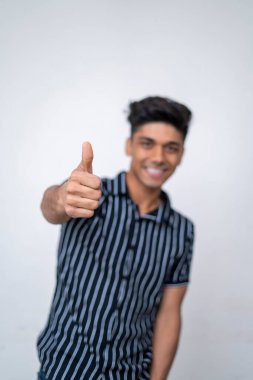 Kameraya başparmaklarını gösteren yakışıklı Asyalı çocuğun eli..