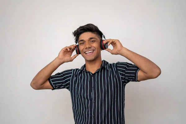 半分のシャツに幸せなインド人男性の肖像 両手でヘッドフォンを持ち 笑顔で音楽を聴いている — ストック写真