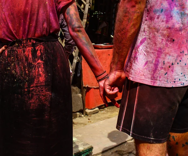 Mathura, Uttar Pradesh / Hindistan - 6 Ocak 2020: Giysilerinde renk lekeleri olan ve Holi festivalini kutlarken el ele tutuşan genç kadın.