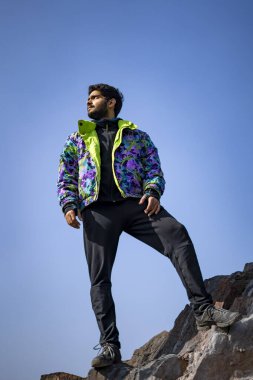 Uçurumun tepesinde kar montu ve eşofman altı giymiş genç Hintli çocuk. Zevk ve özgürlük kavramı.