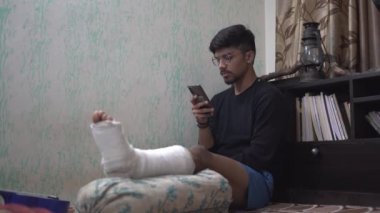 Gece yarısı karanlık bir odada cep telefonu kullanan bir adam. Masa lambası açık..