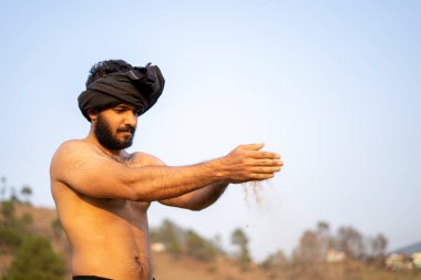 Tarlada çalışan genç Hintli çiftçi. Toprak Tanrısına dua ediyorum..