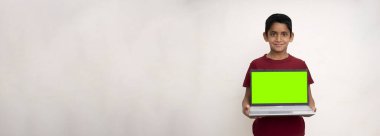 Genç Hintli bir çocuğun elinde yeşil ekranlı bir dizüstü bilgisayar tutarken ve kopyalama alanı olan beyaz izole bir arkaplanda dururken görüntüsü..