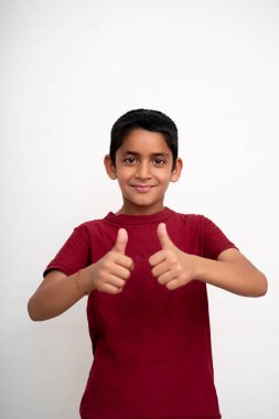Genç Hintli çocuk gülümserken kameraya başparmağını gösteriyor. Küçük çocuk eğitimi konsepti.