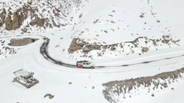 Güzel bir dağ manzarası olan karlı buz yolunda giden bir kamp aracının hava görüntüsü..