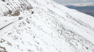 Karlı buz yolunda giden karlı bir kardan aracın hava görüntüsü. Güzel bir dağ manzarası var. Kamp aracı ladakh 'a tırmanıyor..