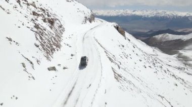 Karlı buz yolunda giden karlı bir kardan aracın hava görüntüsü. Güzel bir dağ manzarası var. Kamp aracı ladakh 'a tırmanıyor..