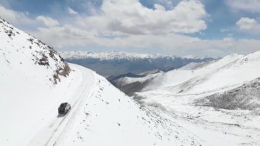 Karlı buz yolunda giden karlı bir kardan aracın hava görüntüsü. Güzel bir dağ manzarası var. Kamp aracı ladakh 'a tırmanıyor..