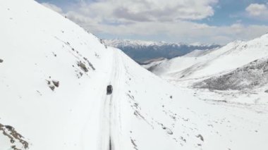 Karlı buz yolunda giden karlı bir kardan aracın hava görüntüsü. Güzel bir dağ manzarası var. Kamp aracı ladakh 'a tırmanıyor..