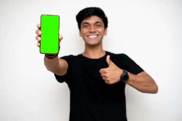 携帯電話を持ってるインド人の少年が画面を指差してる モックアップ用の緑の画面を持つ携帯電話 — ストック写真