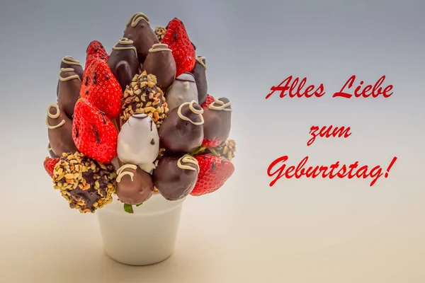 Alles Liebe zum Geburtstag yazan kırmızı harfli doğum günün kutlu olsun. Bir demet yenilebilir çiçek, beyaz üzerine izole edilmiş çikolata soslu çilek aranjmanı.