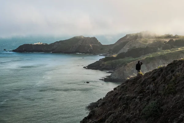 Açık Havada Giyinmiş Bir Adam Okyanusun Kıyısındaki Bir Tepede Dikiliyor - Stok İmaj