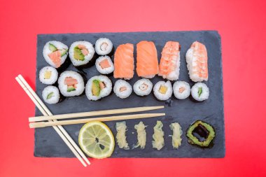 İçinde somon, karides, avokado, yumurta, limon olan birçok çeşit suşi içeren taş masa.