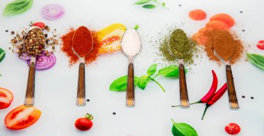 Renkli masa örtüsü üzerinde baharatlı kaşıklar, üst görünüm.