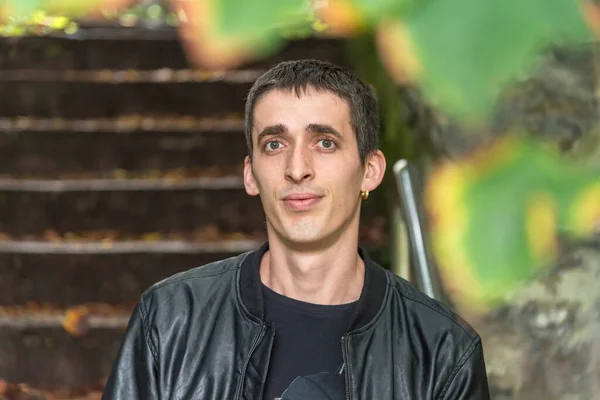 Bilbao 'da poz veren çocuk, sahilin yanındaki merdivenlerde siyah bir tişört ve siyah deri ceket giymiş.