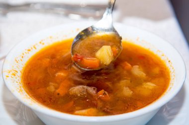 Beyaz tabakta et çorbası, aynı renkte bir masa örtüsü ile bir restoran masasında.