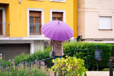 Yağmurda sırtında şemsiye olan bir kadın.