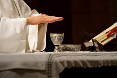 Ayin sırasında rahip ellerini kadehte tutar.