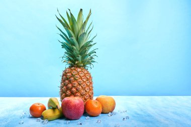 Mavi arkaplanda meyve ve kopya alanı ile çevrili ananas