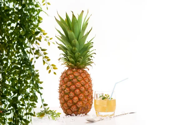 Meyve suyunun yanında beyaz arka planda yeşillik ve kopyalama alanı olan ananas.