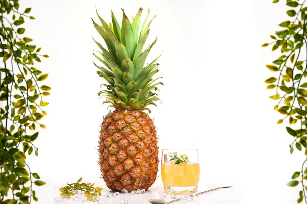 Meyve suyunun yanında beyaz arka planda yeşillik ve kopyalama alanı olan ananas.