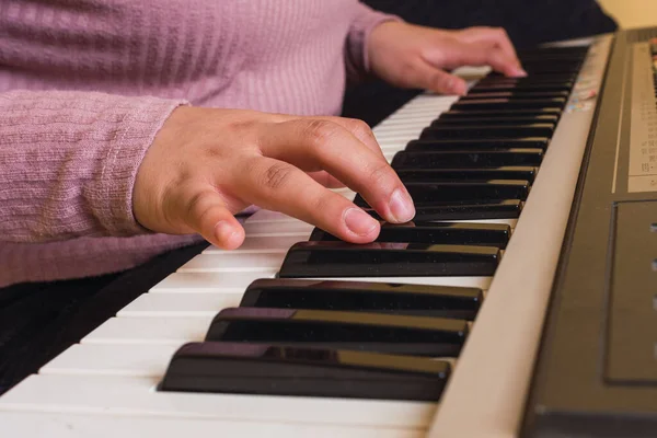 紫のセーターを着た少女がピアノを弾いていて — ストック写真