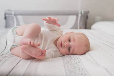 Beyaz çarşaflı, kocaman bir yatakta uyuyan sevimli bir bebek.