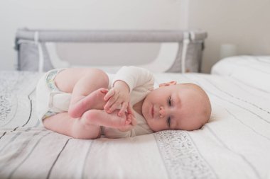 Beyaz çarşaflı, kocaman bir yatakta uyuyan sevimli bir bebek.