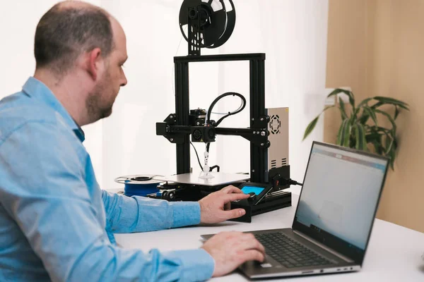 Jovem engenheiro no laboratório ajustando componentes de impressoras 3D — Fotografia de Stock