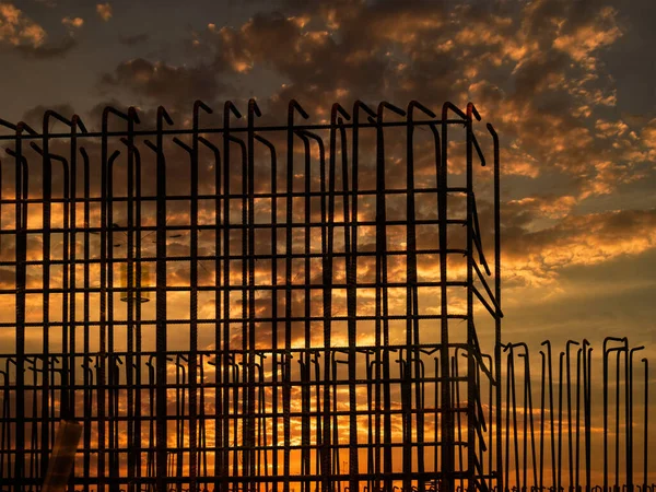 Silhouette of steel rebar of flyover bridge under construction with golden sky background.