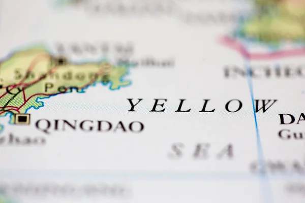 Shallow depth of field focus on geographical map location of Yellow Sea off coast of China on atlas