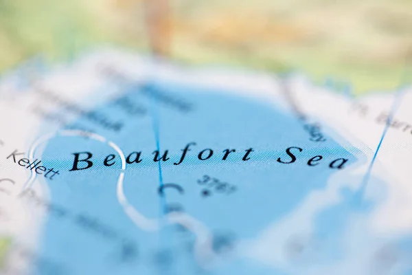 Shallow depth of field focus on geographical map location of Beaufort Sea off coast of Canada on atlas