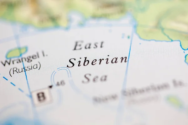 Shallow depth of field focus on geographical map location of East Siberian Sea off coast of Siberia on atlas